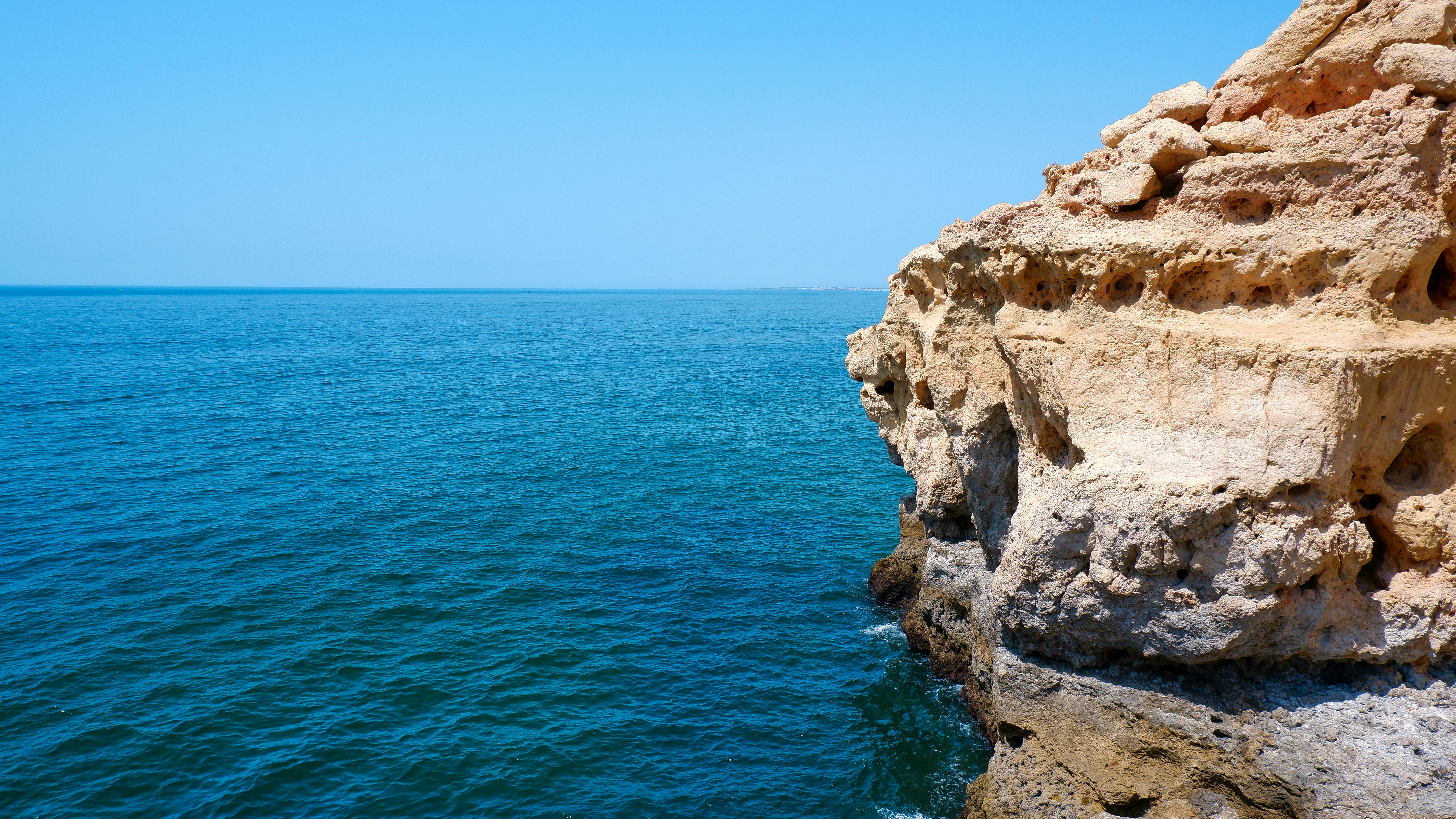 Wide shot of the Atlantic meeting warm limestone cliffs on a clear day